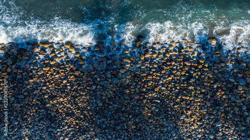 Overhead view of a beach coastline in Mexico, with blue water and rocks, in the morning.