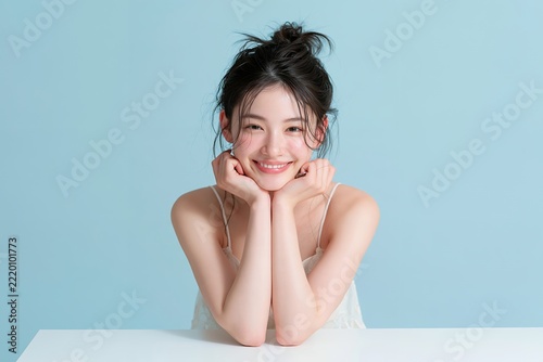 美しい笑顔で目線の日本人女性水色背景の美容スキンケアポートレート
