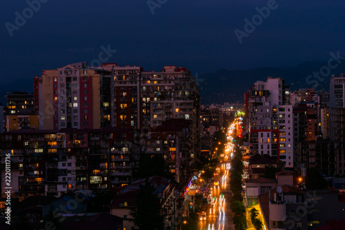 View of city highway traffic - street with typical residential buildings, fast cars and light trails in Batumi, Georgia in the evening. Rush hour, urban and transportation concept