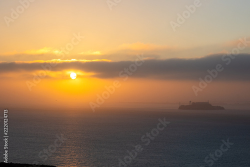 San Francisco, California, September 11, 2016: San Francisco looking at the sunrise on the bay with beautiful red clods and Alcatraz Island Prison on the lower right of the scene.