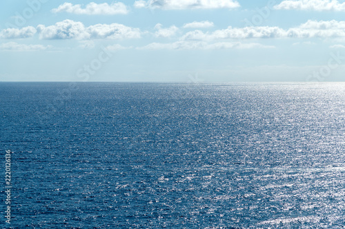 Expansive sea reflecting sunlight under cloudy sky horizon