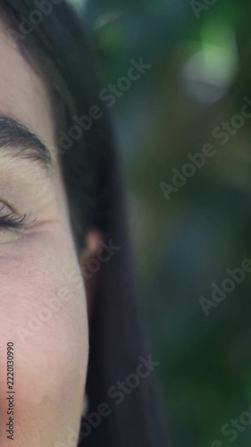 Vertical video: Squinting left-side woman moving eye and lifting cheek from dappled sun, copy space
