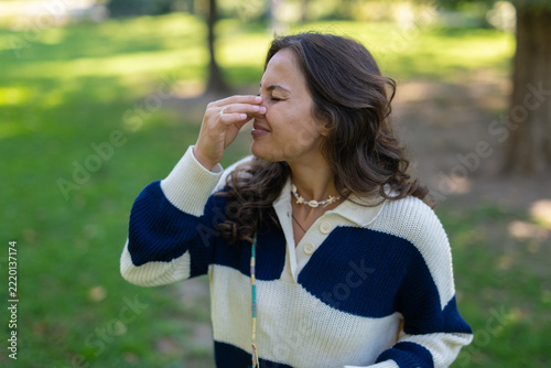 Fotografie Woman pinching nose experiencing bad smell in park