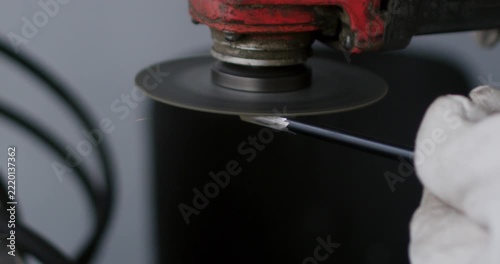Close up macro view of worker sharpening metal rod with angle grinder disc