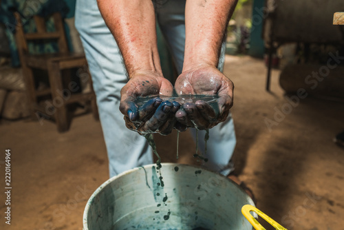 A Mayan artisan displays the famous, authentic Maya Blue pigment in his hands, letting the water-diluted paint run through his fingers.
