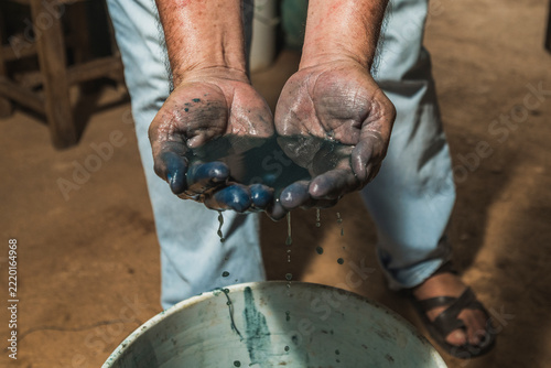 A Mayan artisan displays the famous, authentic Maya Blue pigment in his hands, letting the water-diluted paint run through his fingers.
