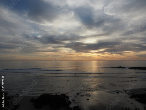 cloudy sunrise on Ogunquit beach in Maine with surfers