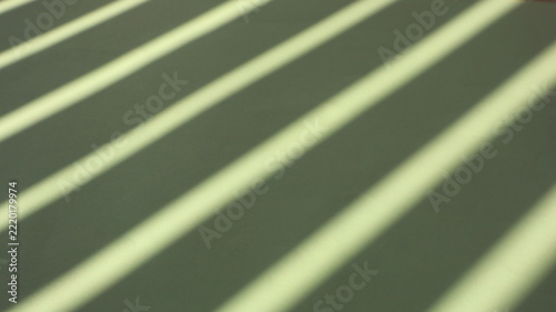 Colorful paper sheets with dramatic linear fence shadows cast by warm natural sunlight