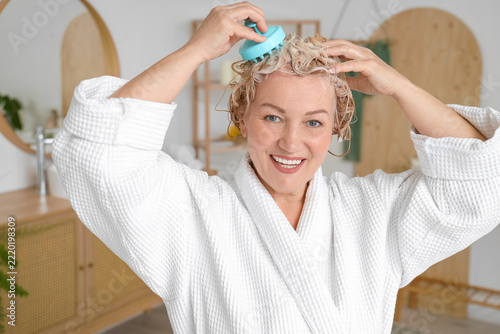 Self care and healthy aging, mature woman using a scalp massager with shampoo...