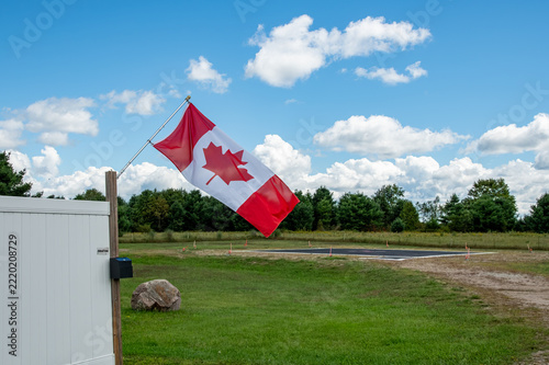 Canadian Flag Flying on a Fence Beneath Beautiful Clouds