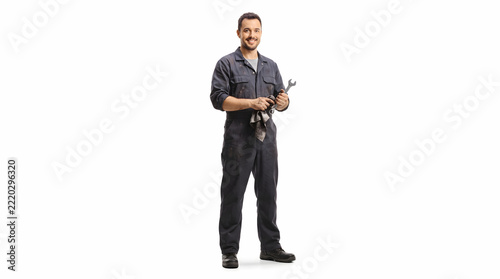 Smiling mechanic holding a wrench and rag standing isolated on white background