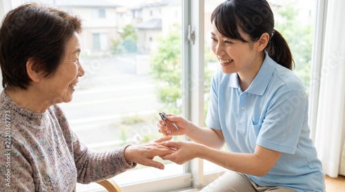 介護施設で高齢女性と笑顔で会話しながら爪切りケアを行う日本人女性の介護福祉士