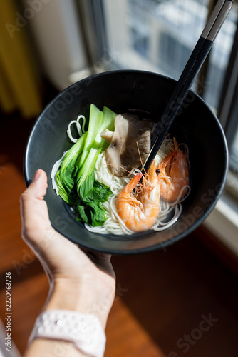 Hand Holding Shrimp and Vegetable Noodle Soup Bowl for Dinner