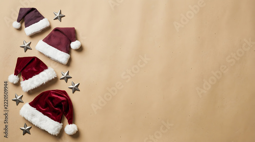 Red santa hats and silver stars festive christmas holiday composition on beige paper background