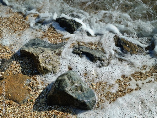 Sticker sea waves crashing on stony beach shore
Close-up of wet coastal stones and pebbles with white foaming sea water washing over the sandy shore