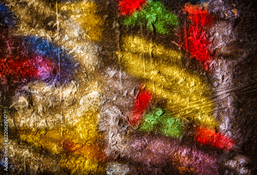 Colorful light from ancient stained glass illuminates stone wall