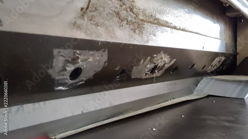 Heavy duty industrial paper guillotine cutter slicing a thick stack of printed paper in a printing workshop