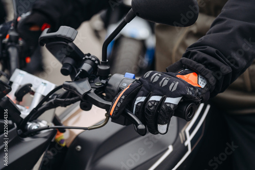 man hand in black leather glove on motorcycle handle, close up view, safety on road, riding motorcycle concept