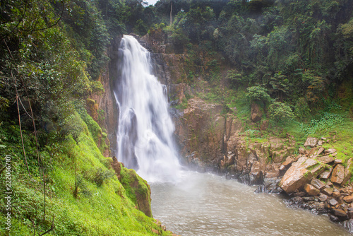 Beautiful Haew Narok waterfall flowing . A scenic view of Haew Narok waterfall cascading down a high rocky cliff into a rushing river stream surrounded by green forest in Khao Yai, Thailand.