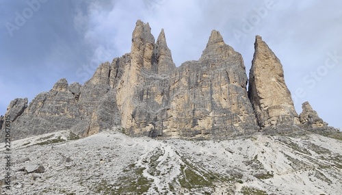 Tre Cime di Lavaredo south faces with hiking trails on scree slopes under dramatic clouds, Dolomites, Italy