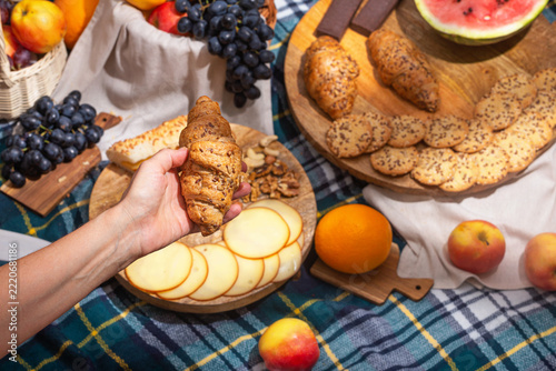 Close-up view of a picnic with food laid out and hands holding food, selective focus. The concept of summer outdoor recreation on the weekend