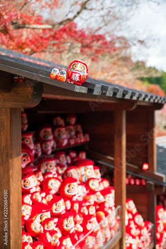 Daruma dolls on cabin roof of Katsuo-ji temple by colorful fall leaf, Osaka