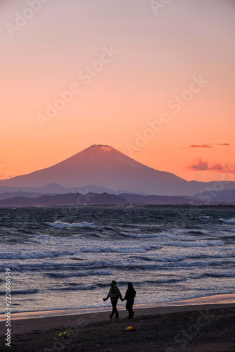 夕焼けの富士山と手をつないで歩く二人｜江の島のロマンチックな旅行・デート素材