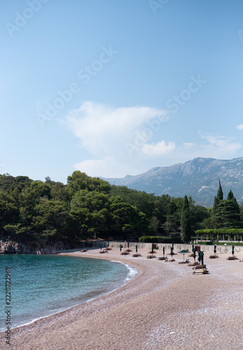 Scenic view of Milocer Beach in Montenegro with closed beach umbrellas and lounge chairs arranged along the shore