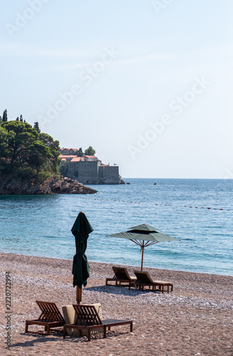 Scenic beach scene in Montenegro featuring wooden sun loungers and umbrellas on a pebbly shore
