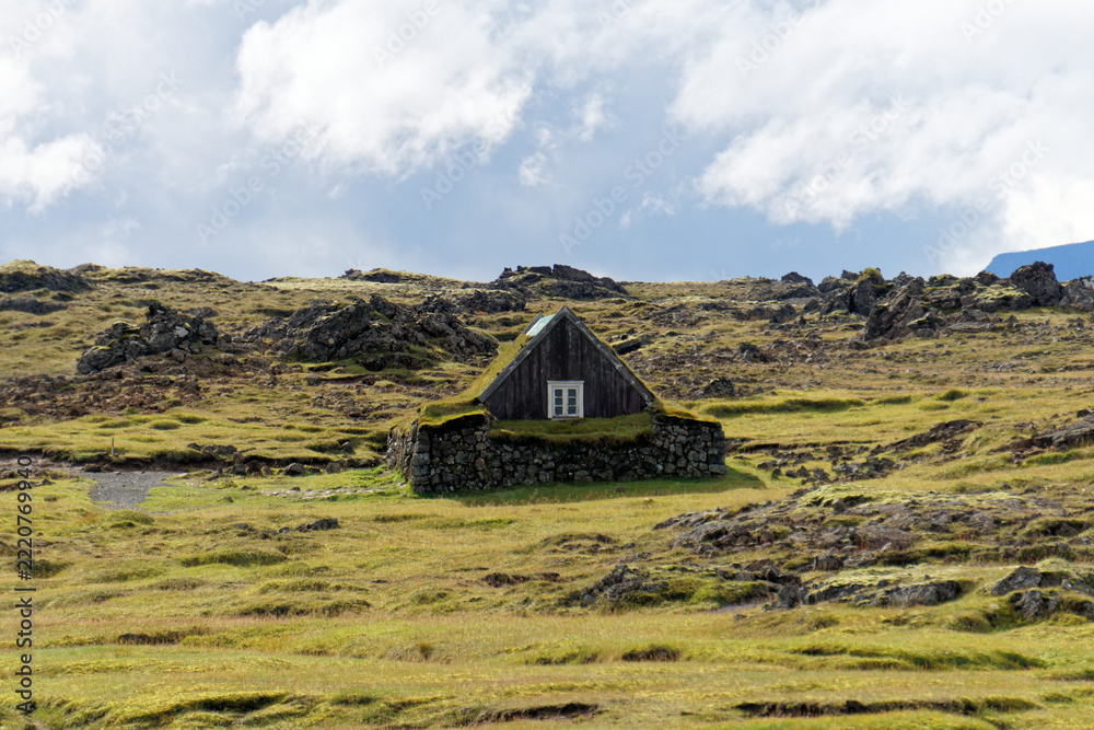 Obraz premium Turf roofed hut on a moss covered heath under dramatic sky
