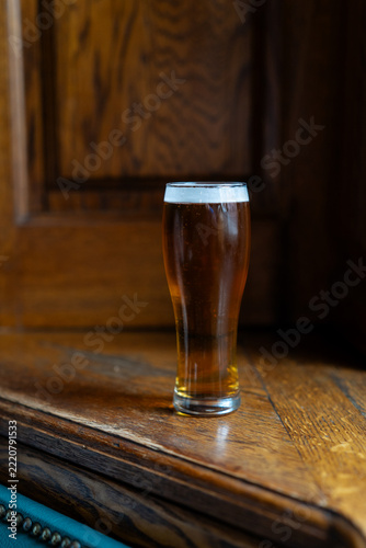 Glass of non alcoholic light beer on dark wood window sill