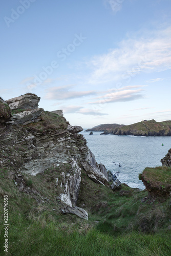 Rugged coastal landscape overlooking the Atlantic Ocean near Baltimore in West Cork Ireland during a calm afternoon with rocky cliffs and green hills.