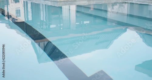 Camera is pulling back and tilting, revealing pool with T marker, steps, patio and solar panels