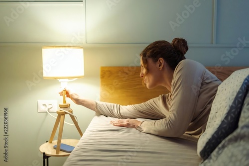 Woman Switching Off Bedside Lamp Before Sleep in Cozy Bedroom