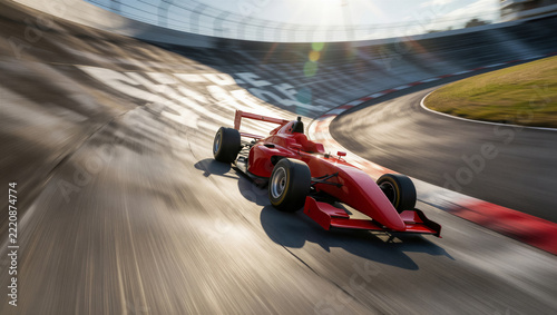 A red race car speeds around a banked track. Motion blur captures the high-speed competition of sport