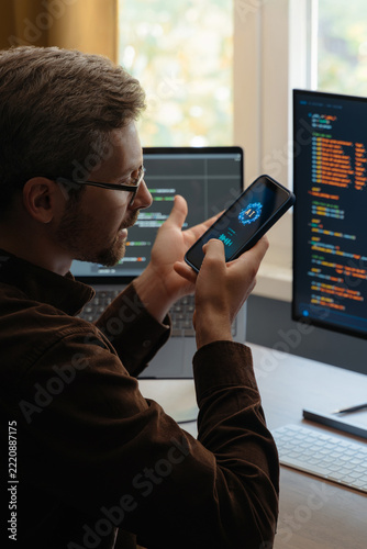 Programmer communicating with an AI agent through a smartphone, using a voice digital assistant on phone for software development and vibe coding. Man talking with Artificial intelligence powered app