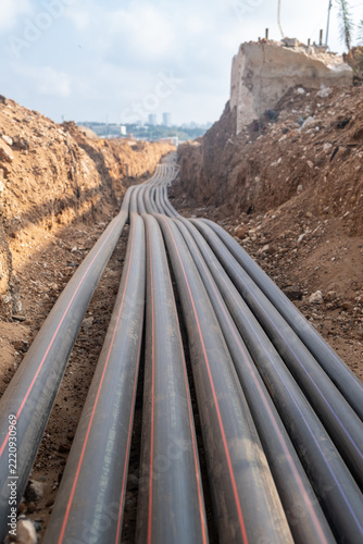 cables and underground conduits laid in excavated trench near city in Israel road construction site highway