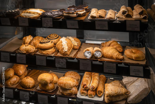 Assortment of fresh croissants, pastries, sweet buns and baked goods displayed in a glass bakery showcase