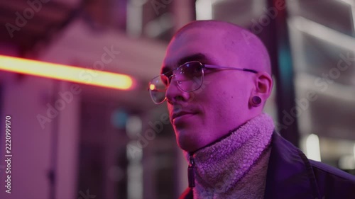A young, fashionable man in the neon lights at night