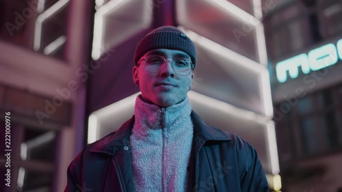 A young, fashionable man in the neon lights at night