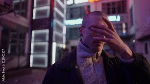 A young, fashionable man in the neon lights at night
