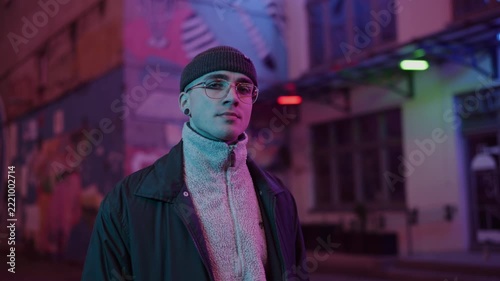 A young, fashionable man in the neon lights at night