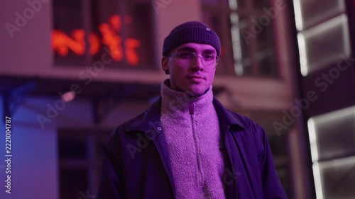 A young, fashionable man in the neon lights at night