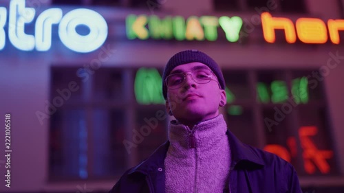 A young, fashionable man in the neon lights at night
