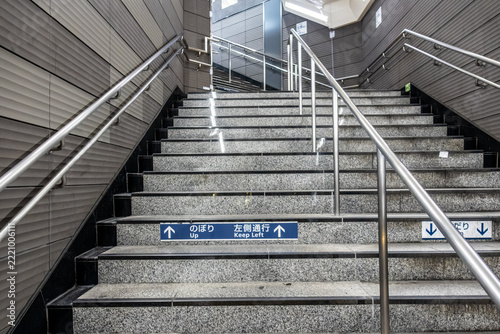 Granite staircase with metal handrails and directional sign at subway station in Tokyo Japan