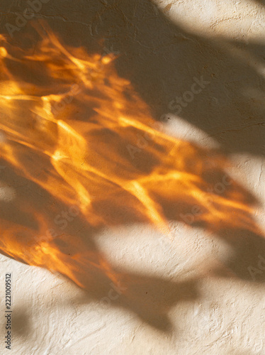 Sunlight filtered through amber glass casting orange shadows on a textured surface