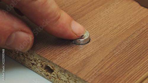 A person assembles a room furniture set with drawers by hand, screwing screws with his fingers. Medium shot.