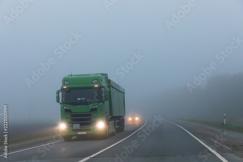 Truck on a country road in the thick fog. Poor visibility conditions on the road.