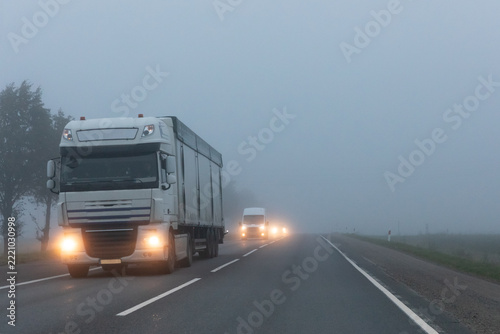 Truck on a country road in the thick fog. Poor visibility conditions on the road.