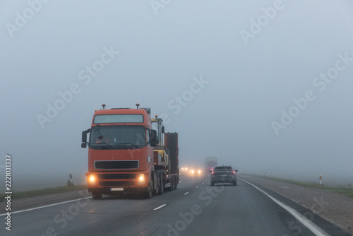 Truck on a country road in the thick fog. Poor visibility conditions on the road.